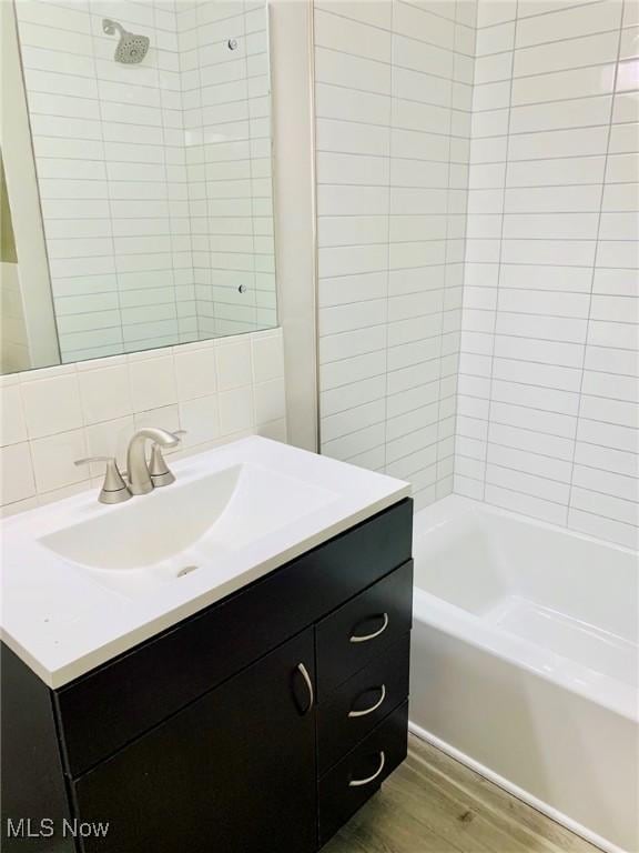 bathroom with backsplash, shower / bath combination, wood finished floors, and vanity