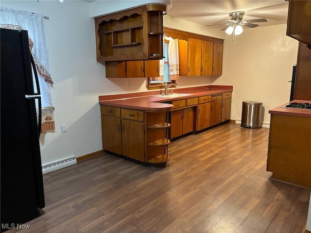 kitchen featuring open shelves, a sink, baseboard heating, freestanding refrigerator, and a ceiling fan