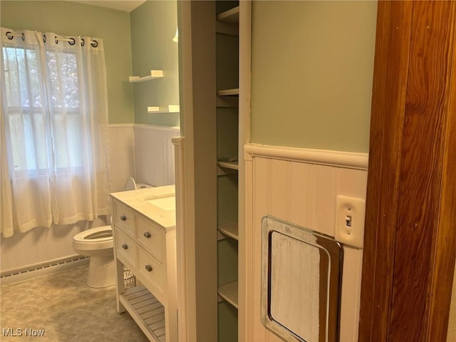 bathroom with vanity, a baseboard radiator, wainscoting, and toilet