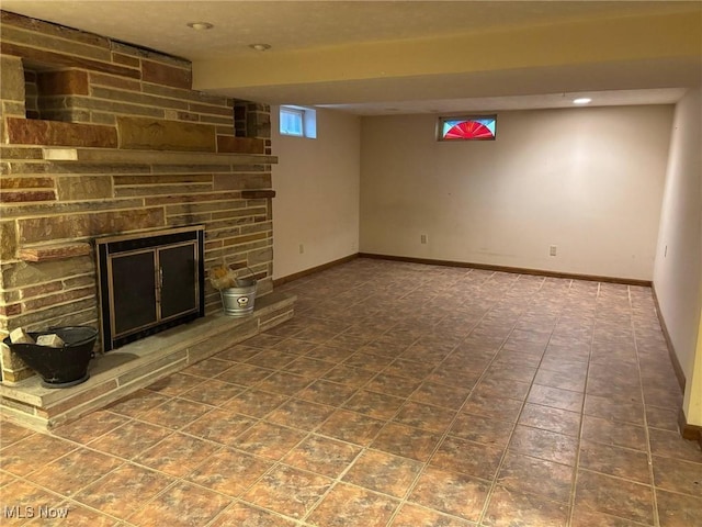 basement featuring baseboards, a fireplace, and recessed lighting