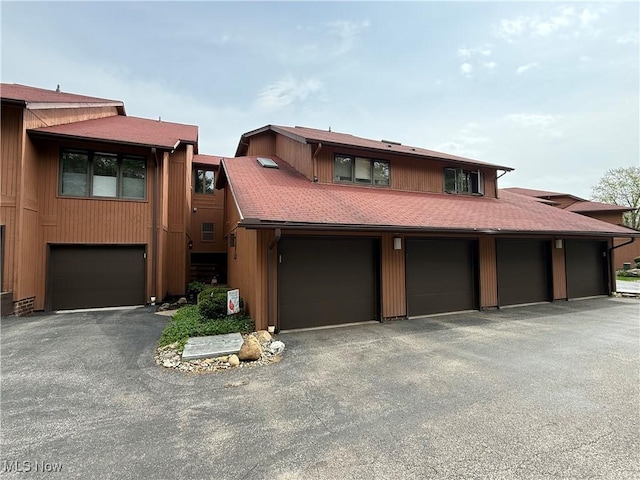 view of front of house with a shingled roof and community garages