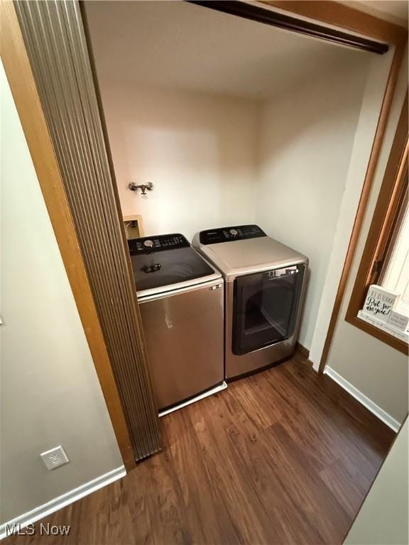 washroom featuring separate washer and dryer, laundry area, baseboards, and dark wood-type flooring