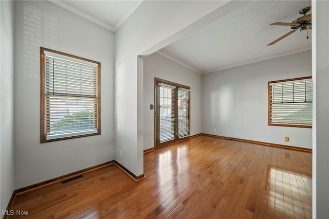 empty room with baseboards, ornamental molding, ceiling fan, and hardwood / wood-style floors