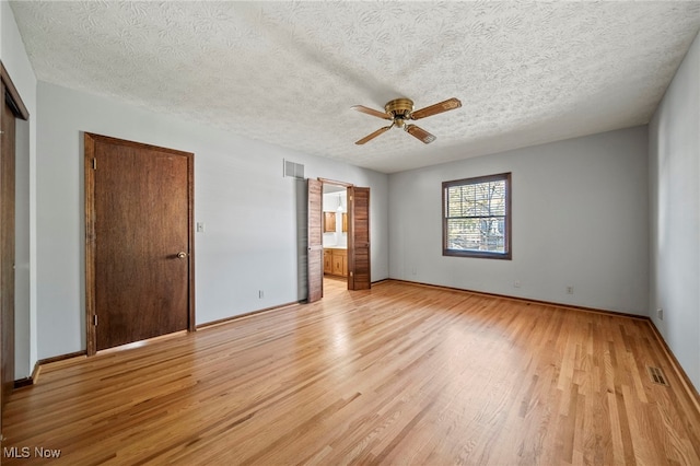unfurnished bedroom with a textured ceiling, baseboards, visible vents, and light wood-style flooring
