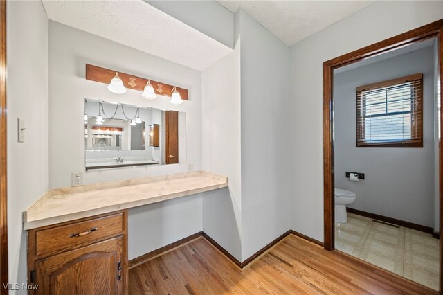 bathroom with toilet, baseboards, wood finished floors, and vanity