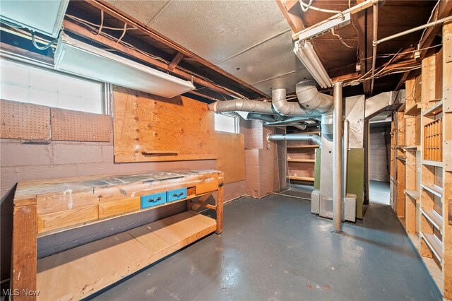 below grade area featuring concrete block wall, a workshop area, and heating unit