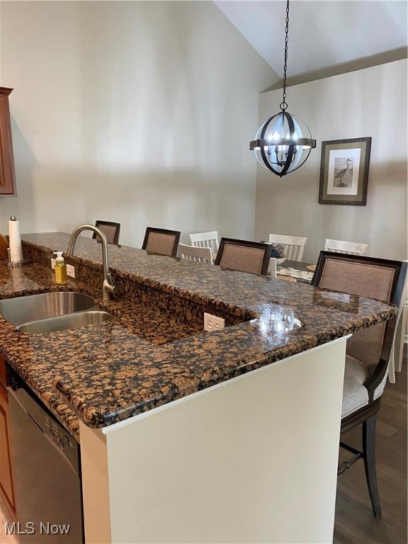 kitchen featuring an inviting chandelier, a sink, a kitchen breakfast bar, and dishwasher