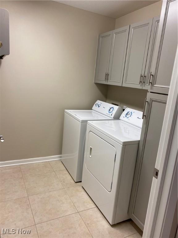 clothes washing area featuring cabinet space, independent washer and dryer, baseboards, and light tile patterned flooring