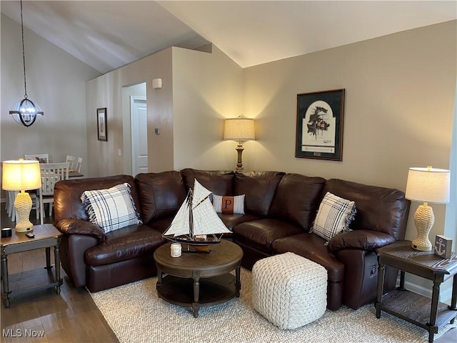living room with a chandelier, wood finished floors, and vaulted ceiling