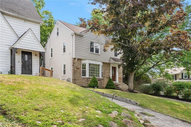 colonial-style house with a front yard and stone siding