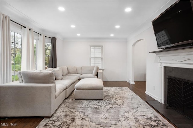 living area featuring recessed lighting, arched walkways, ornamental molding, and dark wood finished floors