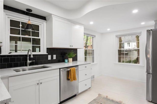 kitchen featuring a sink, appliances with stainless steel finishes, decorative backsplash, and white cabinetry