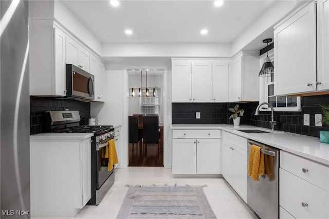 kitchen with decorative backsplash, recessed lighting, white cabinetry, a sink, and appliances with stainless steel finishes