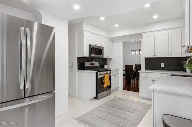 kitchen featuring white cabinets, appliances with stainless steel finishes, a sink, recessed lighting, and decorative backsplash