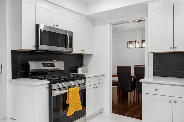 kitchen featuring light countertops, appliances with stainless steel finishes, tasteful backsplash, and white cabinets