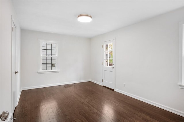 empty room with dark wood-style flooring and baseboards