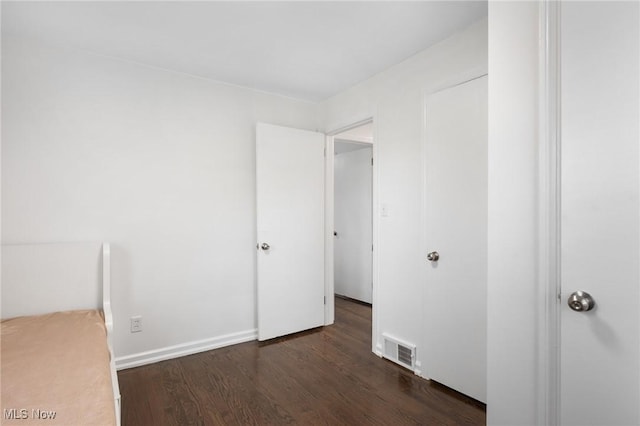 unfurnished bedroom featuring baseboards, visible vents, and wood finished floors