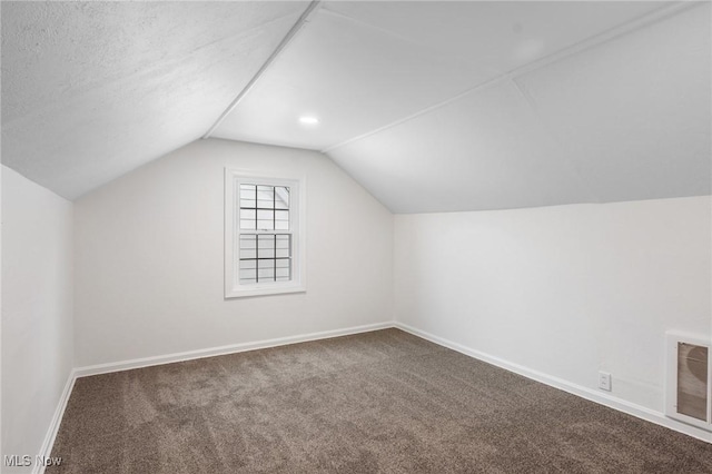 additional living space featuring visible vents, carpet, baseboards, and vaulted ceiling