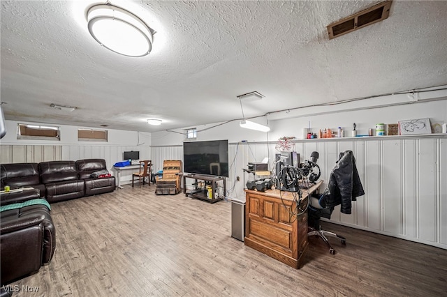 office with a textured ceiling, a decorative wall, wood finished floors, and visible vents