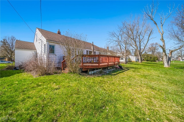 back of house featuring a lawn, a wooden deck, and a chimney