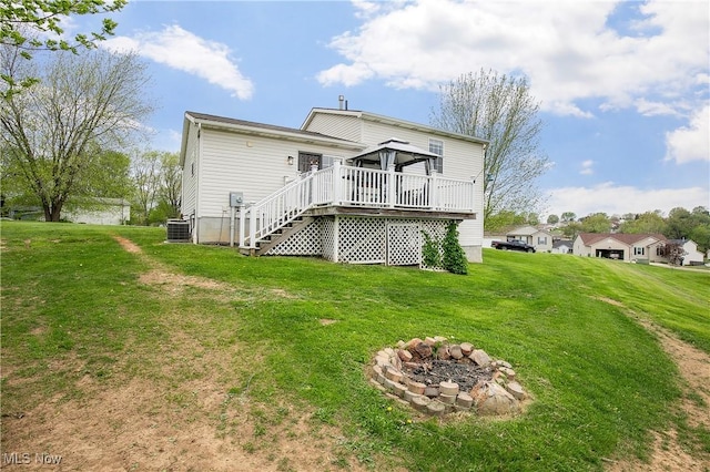 back of house with stairs, a deck, central air condition unit, a lawn, and a fire pit