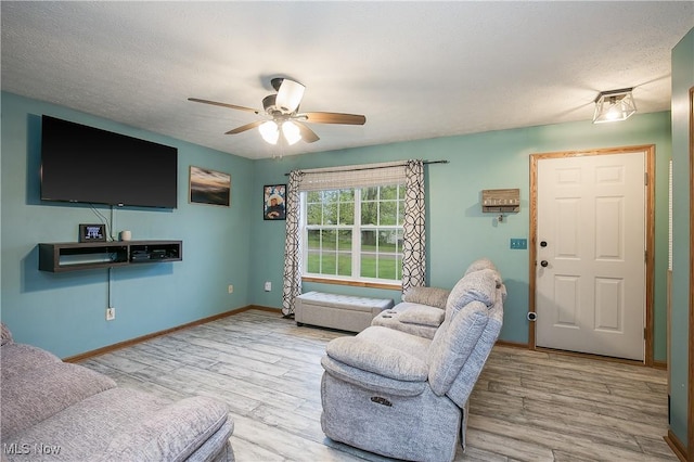 living room featuring a ceiling fan, baseboards, and wood finished floors