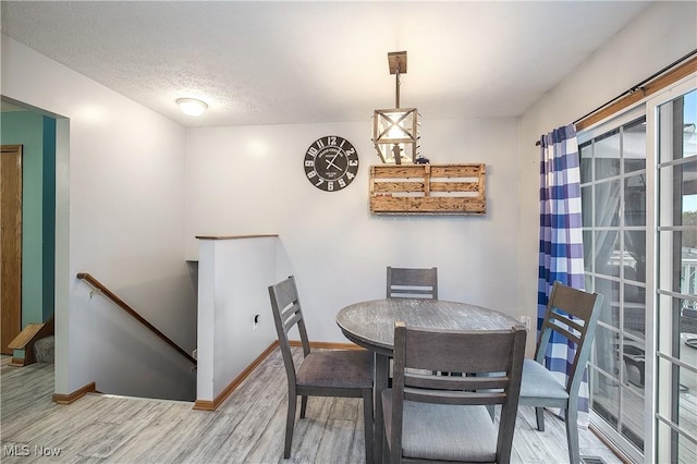 dining room with baseboards, a textured ceiling, and wood finished floors