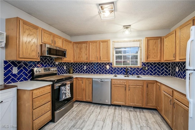 kitchen featuring a sink, appliances with stainless steel finishes, light wood-type flooring, and light countertops