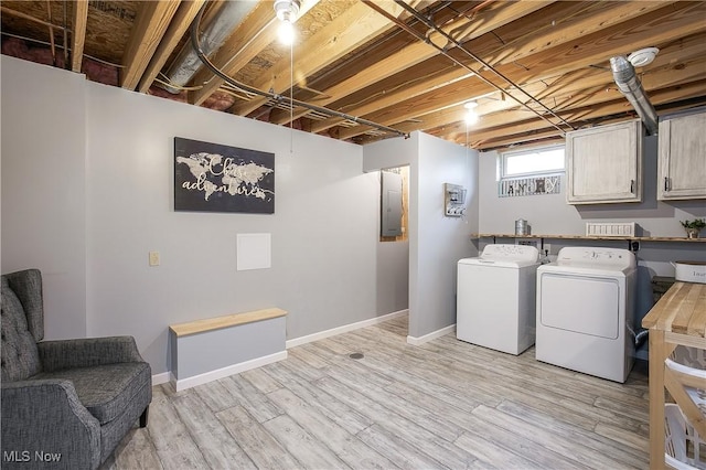 laundry room with cabinet space, baseboards, light wood-type flooring, washing machine and dryer, and electric panel