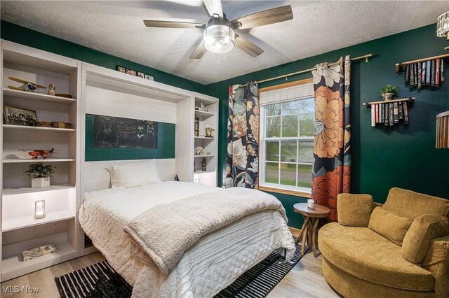bedroom with a ceiling fan, light wood finished floors, and a textured ceiling