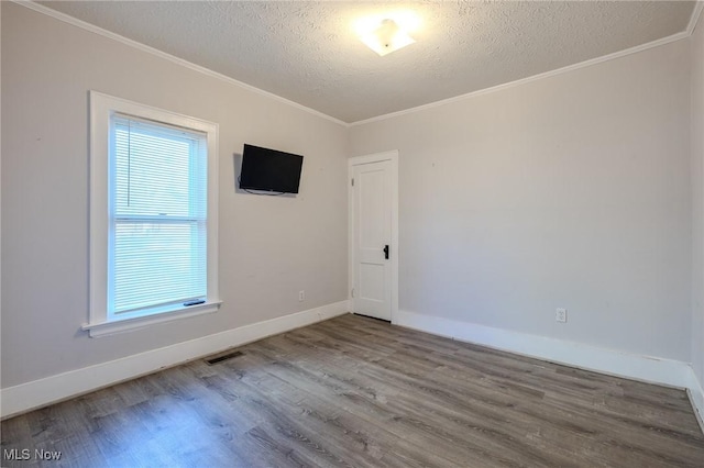 unfurnished room featuring baseboards, a textured ceiling, ornamental molding, and wood finished floors