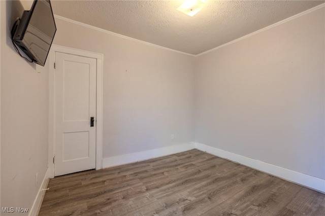 spare room with baseboards, ornamental molding, a textured ceiling, and wood finished floors