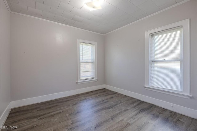 empty room featuring crown molding, baseboards, and wood finished floors