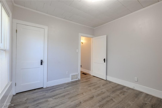 unfurnished bedroom with crown molding, baseboards, wood finished floors, and visible vents