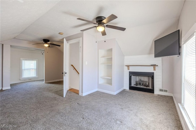 unfurnished living room with a ceiling fan, carpet flooring, lofted ceiling, and visible vents