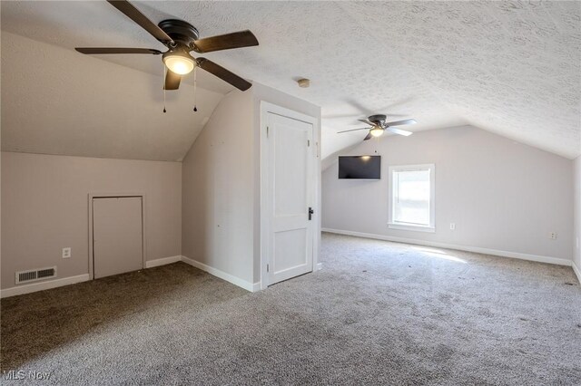 additional living space featuring carpet flooring, a textured ceiling, ceiling fan, and vaulted ceiling