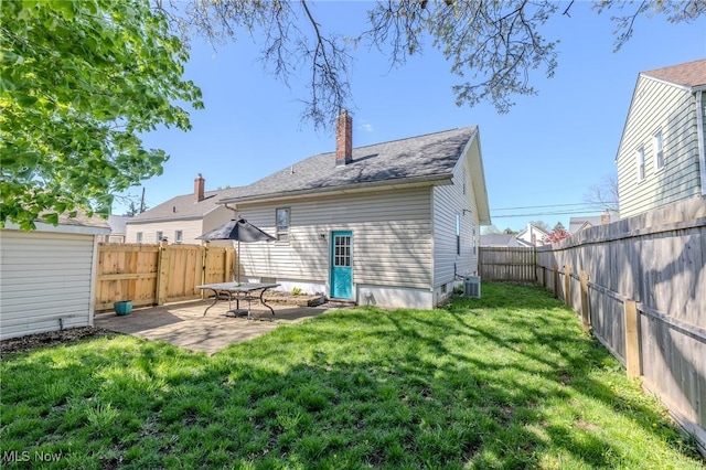 rear view of house with cooling unit, a patio, a fenced backyard, a chimney, and a yard