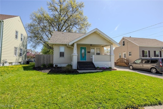 bungalow featuring a porch, a front yard, central AC, fence, and a shingled roof