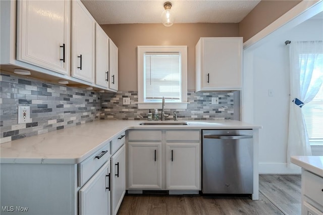 kitchen with a sink, white cabinets, stainless steel dishwasher, and wood finished floors