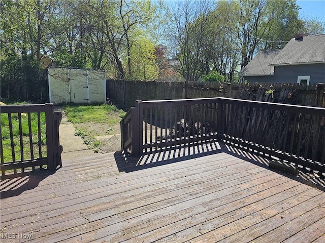 wooden terrace featuring a fenced backyard, an outbuilding, and a storage shed