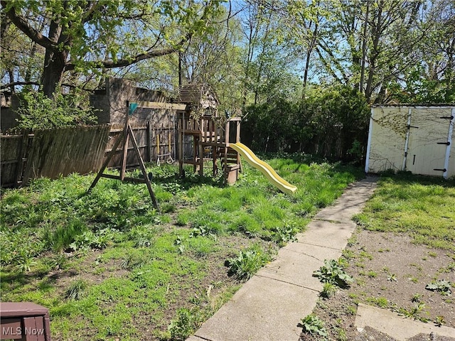 view of jungle gym featuring fence, a storage unit, and an outdoor structure