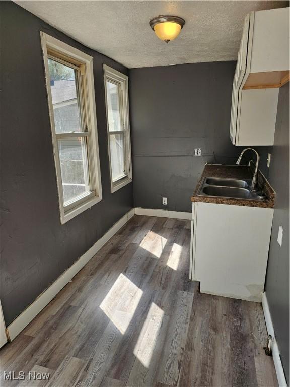 laundry area featuring a sink, baseboards, dark wood-style floors, and a textured ceiling