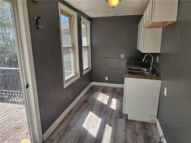 interior space with a sink, baseboards, dark wood-style flooring, and a textured ceiling