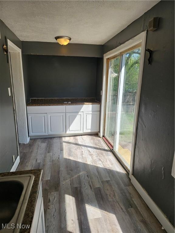 spare room with a sink, a textured ceiling, and wood finished floors