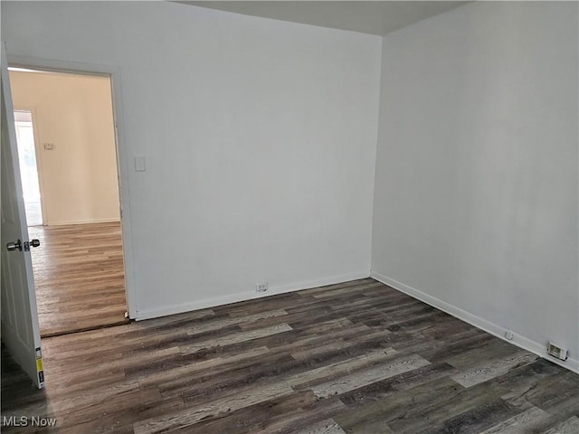spare room featuring dark wood-type flooring and baseboards