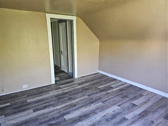additional living space featuring baseboards, dark wood finished floors, and vaulted ceiling