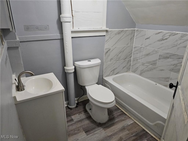 full bath featuring toilet, wood finished floors, a tub to relax in, and vanity