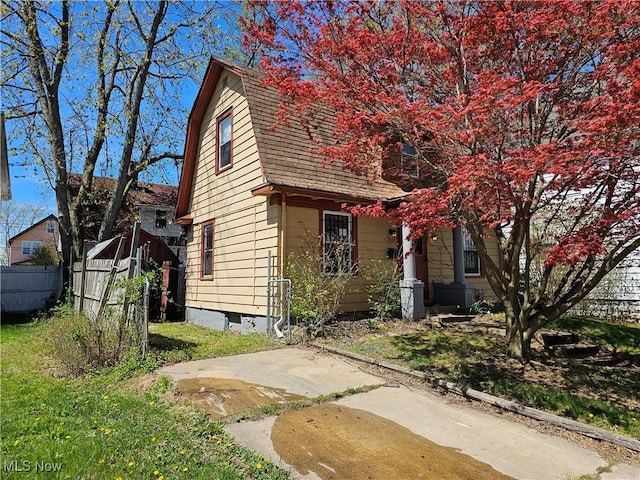 view of front of house featuring fence and a gambrel roof