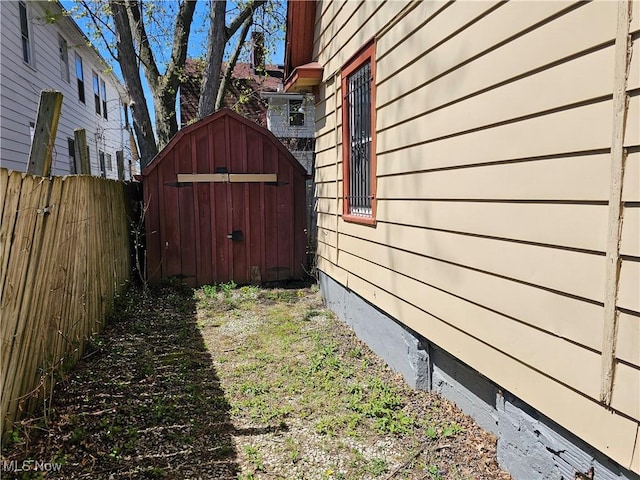 view of property exterior with an outdoor structure, crawl space, fence, and a shed