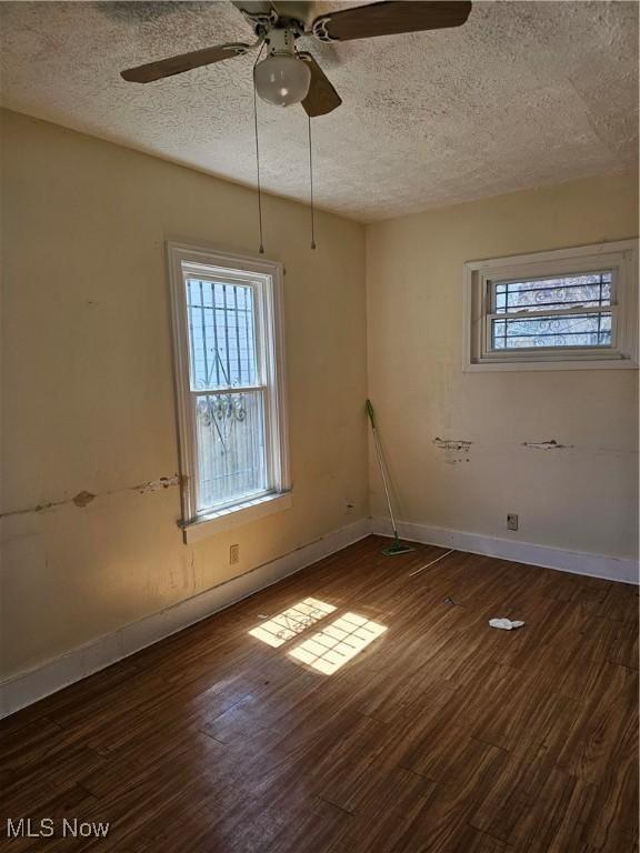 unfurnished room with baseboards, a textured ceiling, ceiling fan, and dark wood finished floors